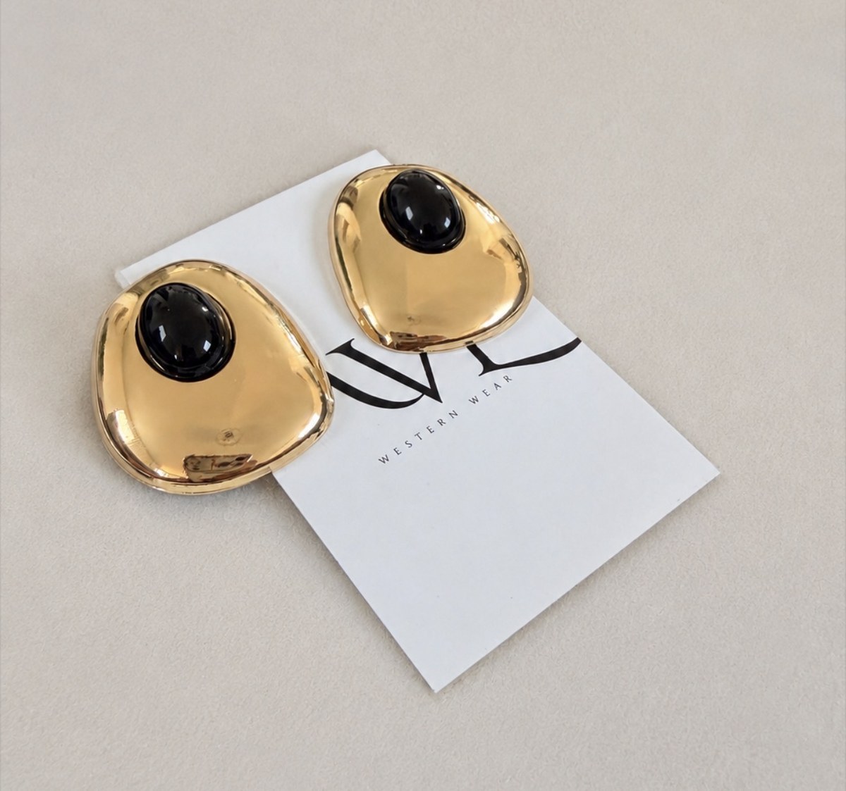 Black and gold statement earrings on AVL card